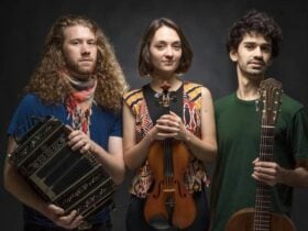 Three musicians holding a small accordion, violin and guitar