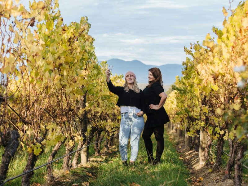 2 women standing between vineyards taking a selfie