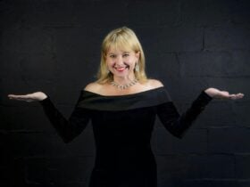 Picture of mezzo soprano Sally-Anne Russell in a black dress with her arms to the sides
