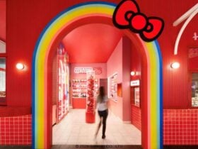 Person walking through a rainbow archway with a large red Hello Kitty bow into a red room.