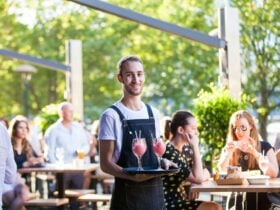 Waiter serving cocktails to tables at Hopscotch