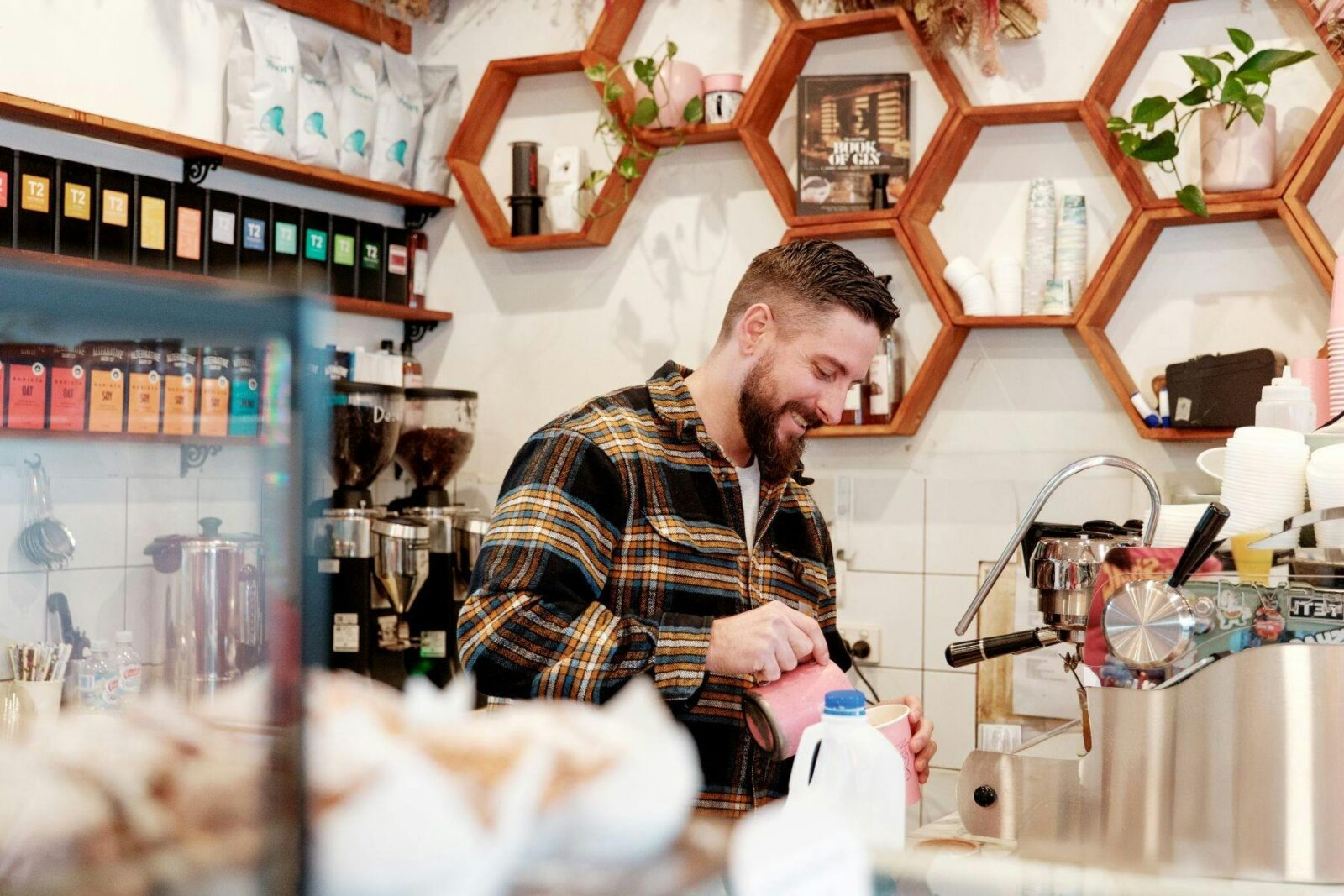 Staff member smiling and making coffees at a machine
