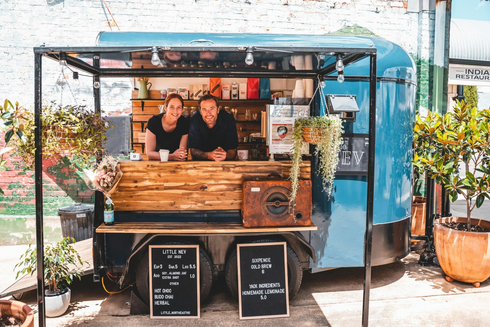 Emma and Michael, the owners of Little NEV are standing inside the van, looking out.