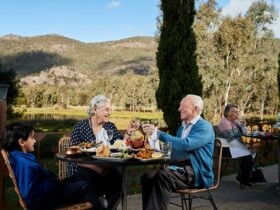 A man, woman and child enjoying an al fresco Indian meal with mountains in the background.