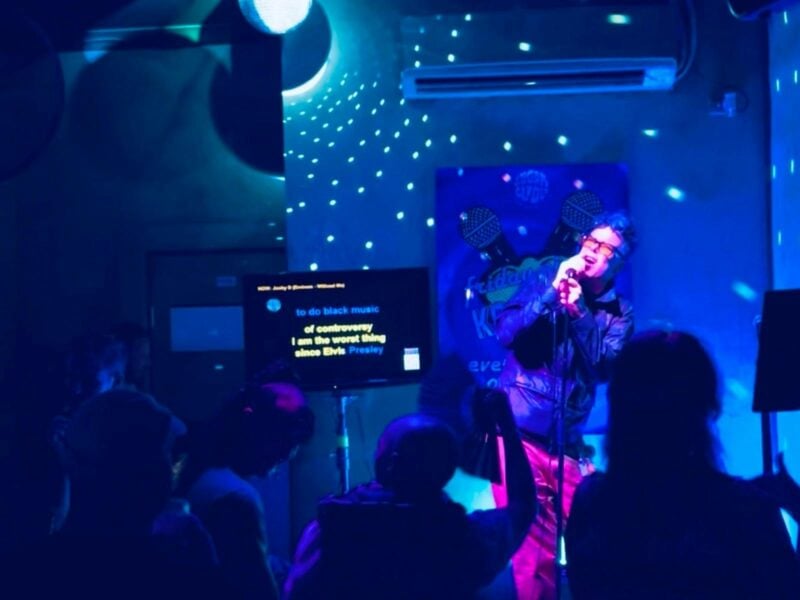 A person performing a karaoke song on stage to an audience of people.
