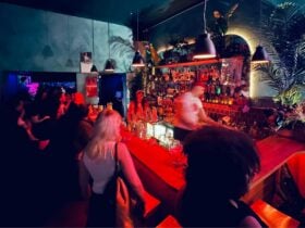 People waiting for drinks while standing at the bar.