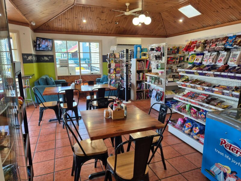 Inside a country cafe with shelves of produce, tables and chairs
