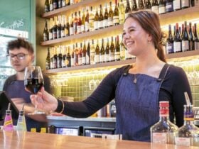 Two people behind a bar serving drinks and smiling
