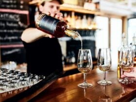 Bartender pouring whisky from a bottle into a tasting glass