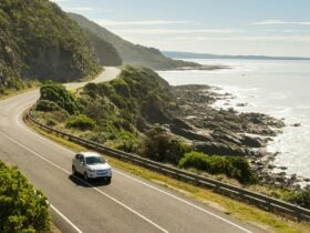 Vehicle driving on a sunny coastal road with the ocean in the background