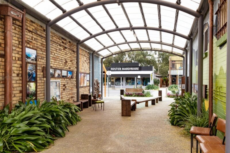 a corridor with brick walls with framed pictures hanging on them and potted plants