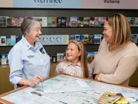 Visitor Services Ambassador showing map to adult and child and smiling