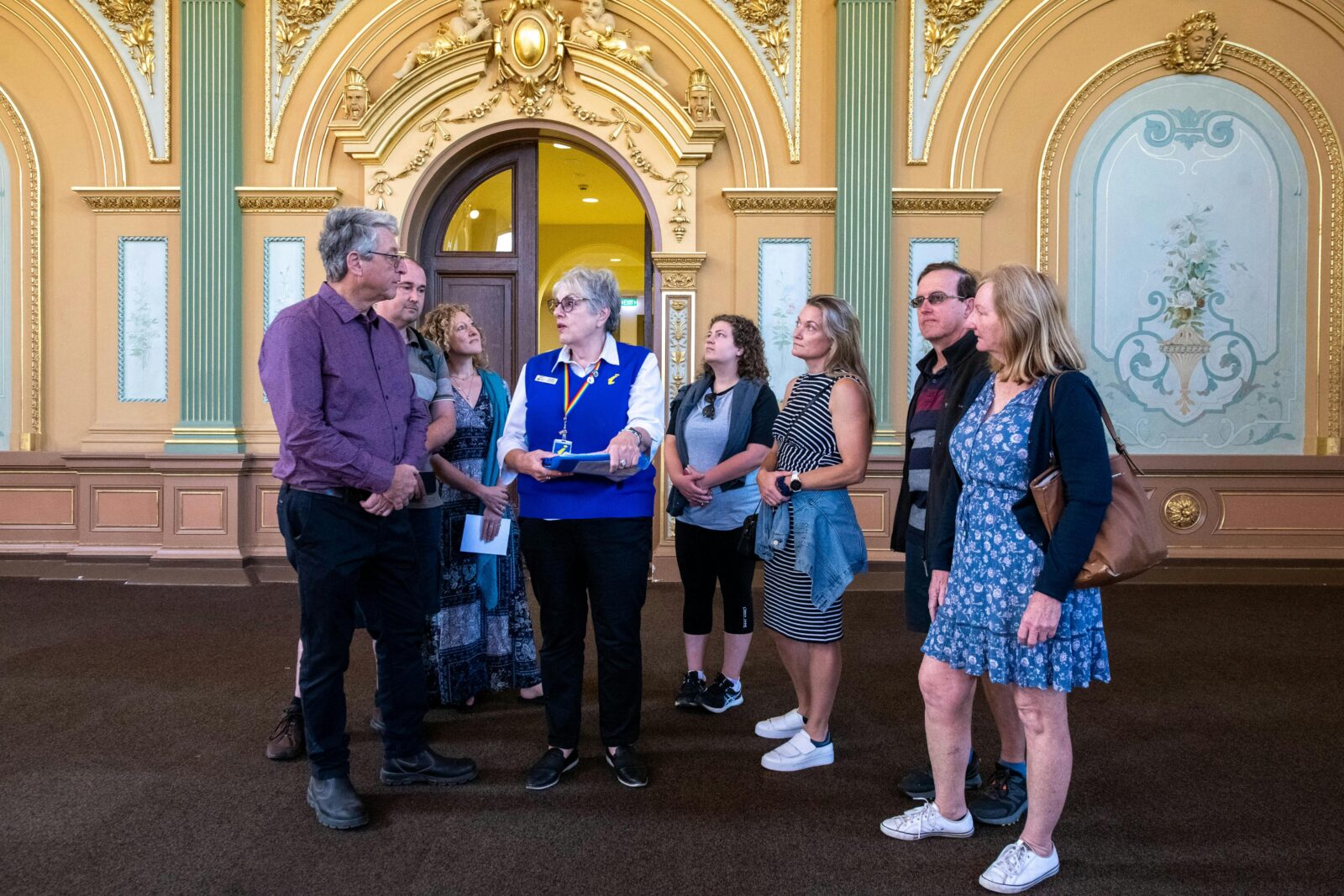 Guide showing engaged visitors the ornate plasterwork, murals and gold leaf work of the hall.