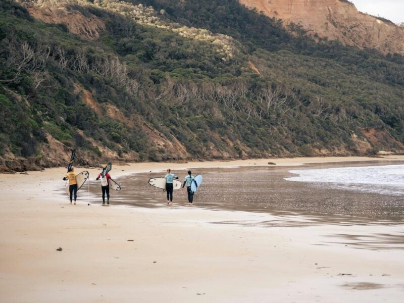 Surf Class of 3 students and a coach walking down a beautiful empty beach near Anglesea and Torquay.