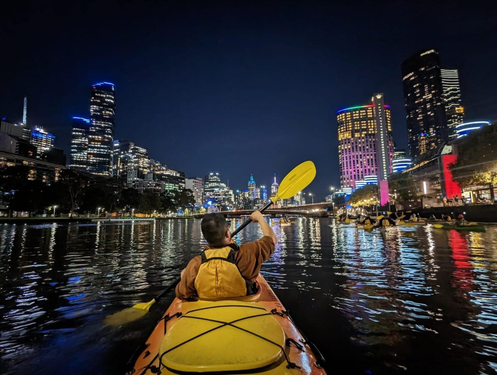 Kayaker on water at night infront of Southbank Crown.