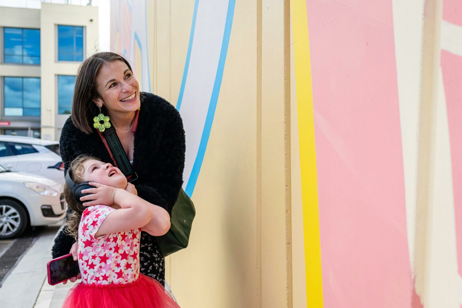 adult and child wearing headphones looking up at mural