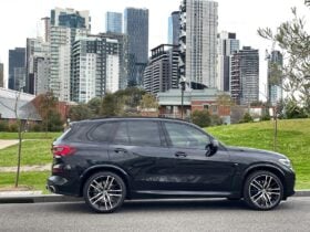 Black BMW SUV photographed against Melbourne city skyline, representing Sublime Chauffeur’s premium