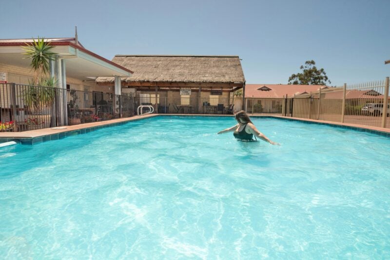 A guest swims in crystal blue water of a swimming pool at Bunbury Apartment Motel