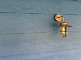 A blue weatherboard wall with a brushed nickel lamp coming out from the wall
