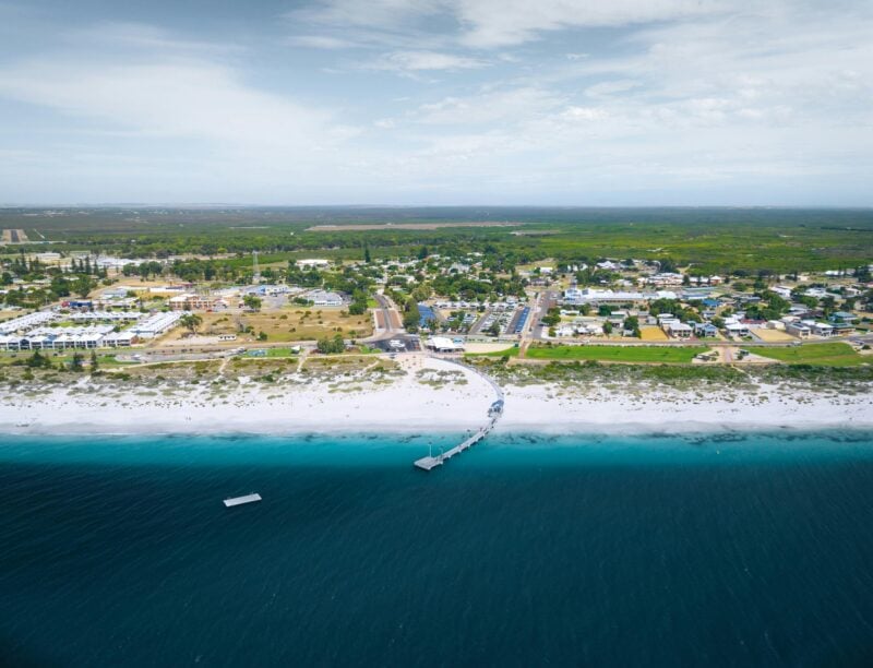 A drone image taken from the ocean facing the land shows Jurien Bay Tourist Park on beachfront