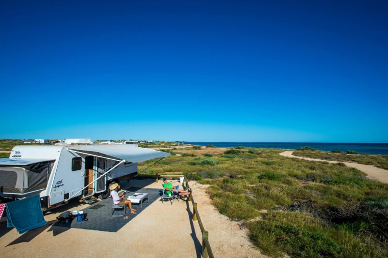 Caravan parked in a cleared space with ocean in the background.