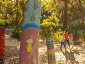 Mother and two children strolling along the nature path with three painted posts in the frontage.