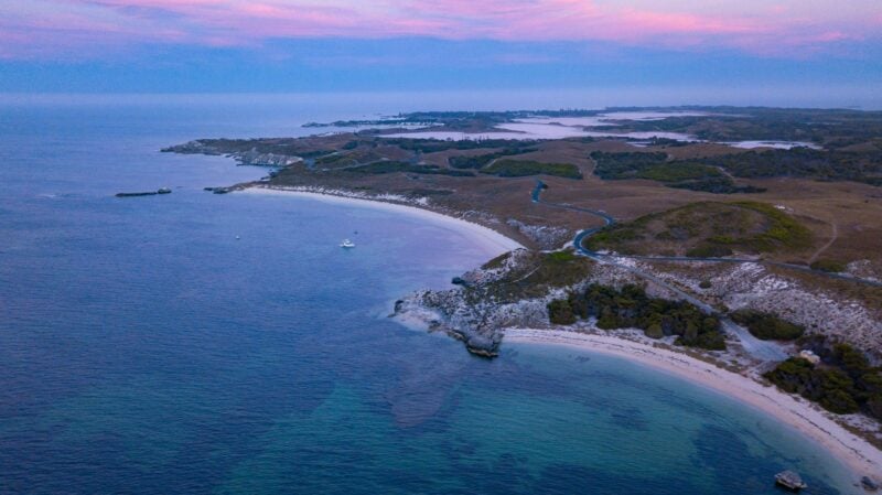 Aerial image of island at sunset with pink clouds.