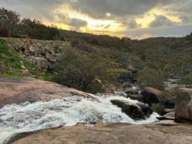 Water cascading over rocks with a view of the hills.