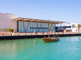 blue water in the foreground with a small boat in the water and a building in the background