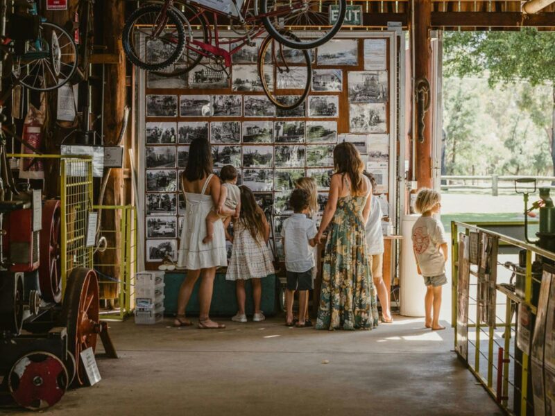 Group of women and children exploring a wall of old machinery and agricultural photographs