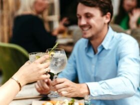 Two people clinking gin and tonic glasses across a restaurant table