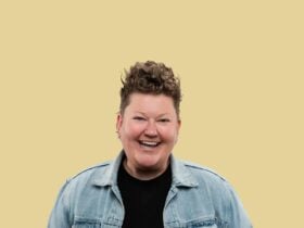 Kirsty Webeck smiling at the camera on a gold background.