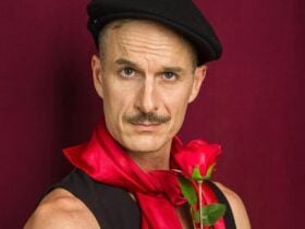 Handsome french romantic man with beret snd rose looks into the camera in a comedically cliched way