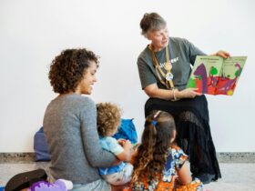A woman and two children listen to a WA Museum Volunteer read a children
