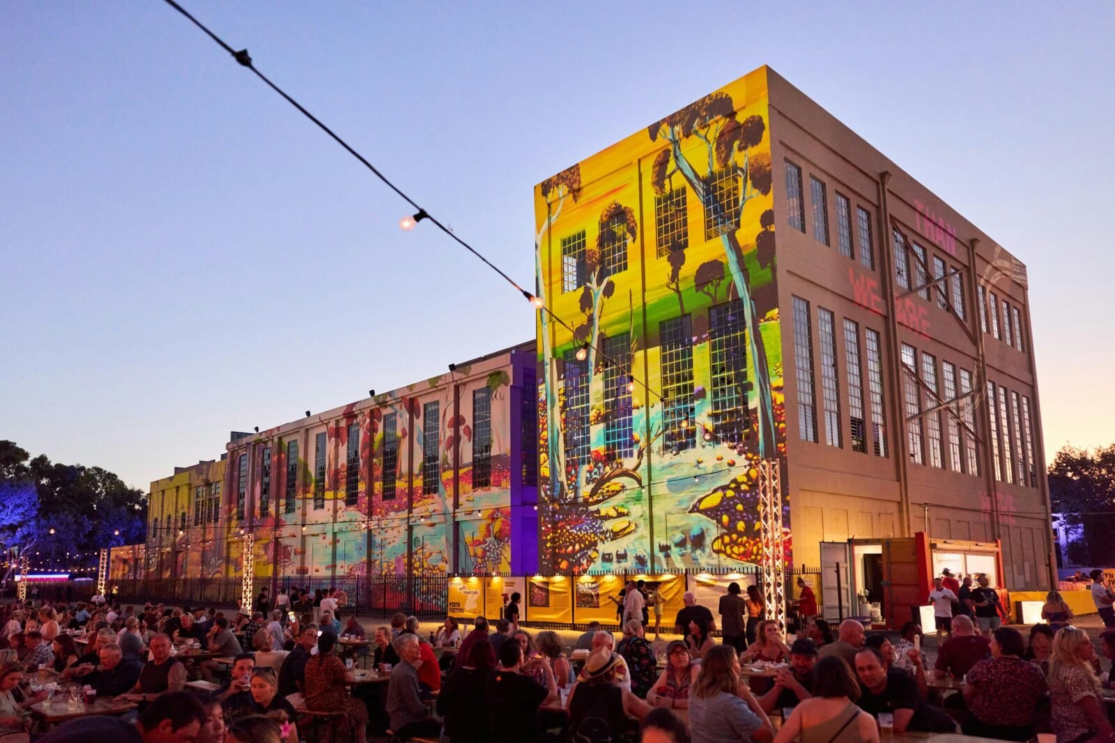 Festival crowd outside the East Perth Power Station, illuminated with First Nations artwork