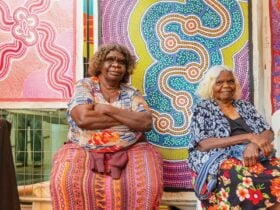 Two female Aboriginal artists sitting next to each other at a vibrant market