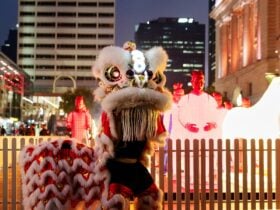A Chinese lion dance takes place in front of a group of brightly lit warrior-shaped lanterns