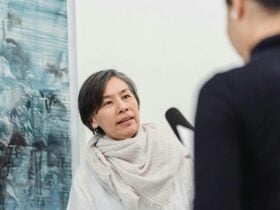 Photograph of an Asian lady wearing a white scarf talking to a unidentifiable man in a black suit.