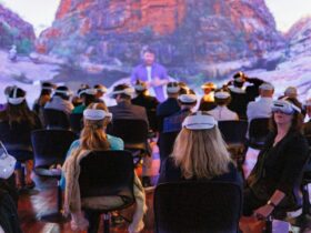 a group of people sittingon chairs in headsets with a projection in the background