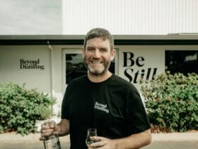 Greg standing outside Beyond Distilling in Busselton, holding a bottle and tasting glass
