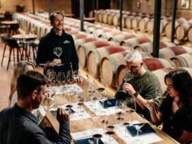 Four guests are seated amongst barrels, sipping wine at a Cape Mentelle wine tasting