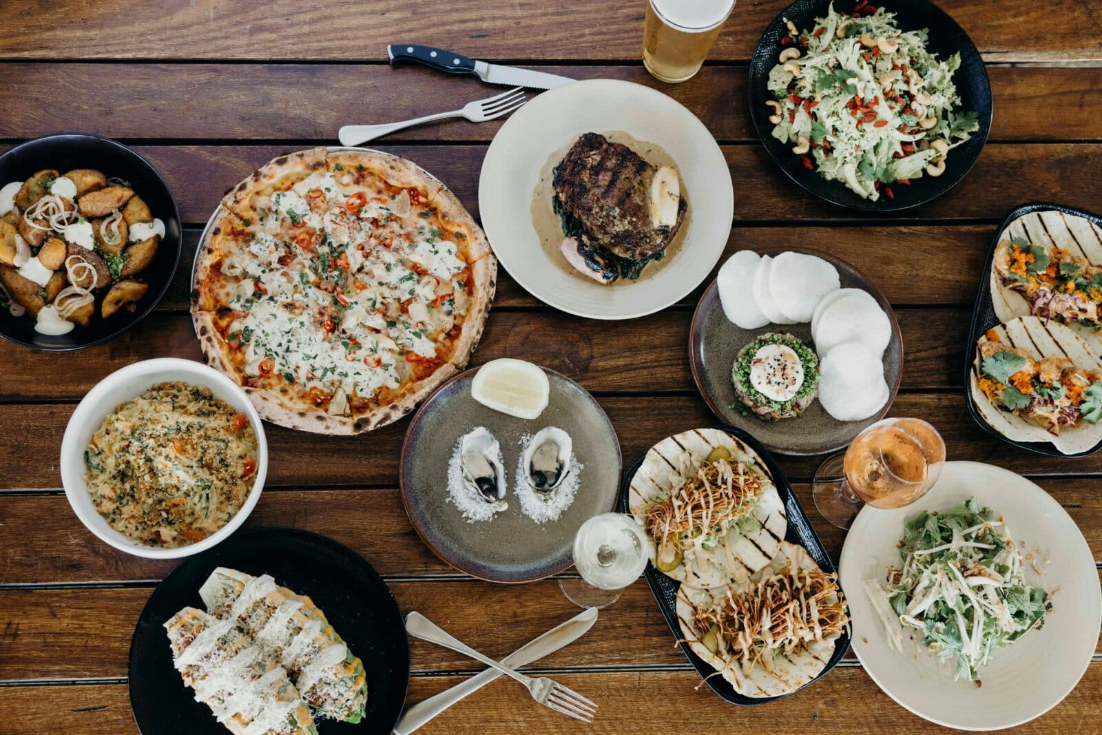 Long table at Eagle Bay brewery, full of lunch staples including pizza, tacos and steak.