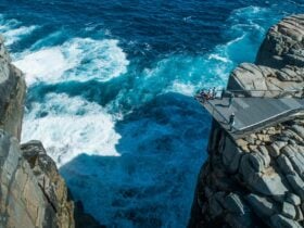 People standing on a platform overlooking the ocean between huge granite rocks.