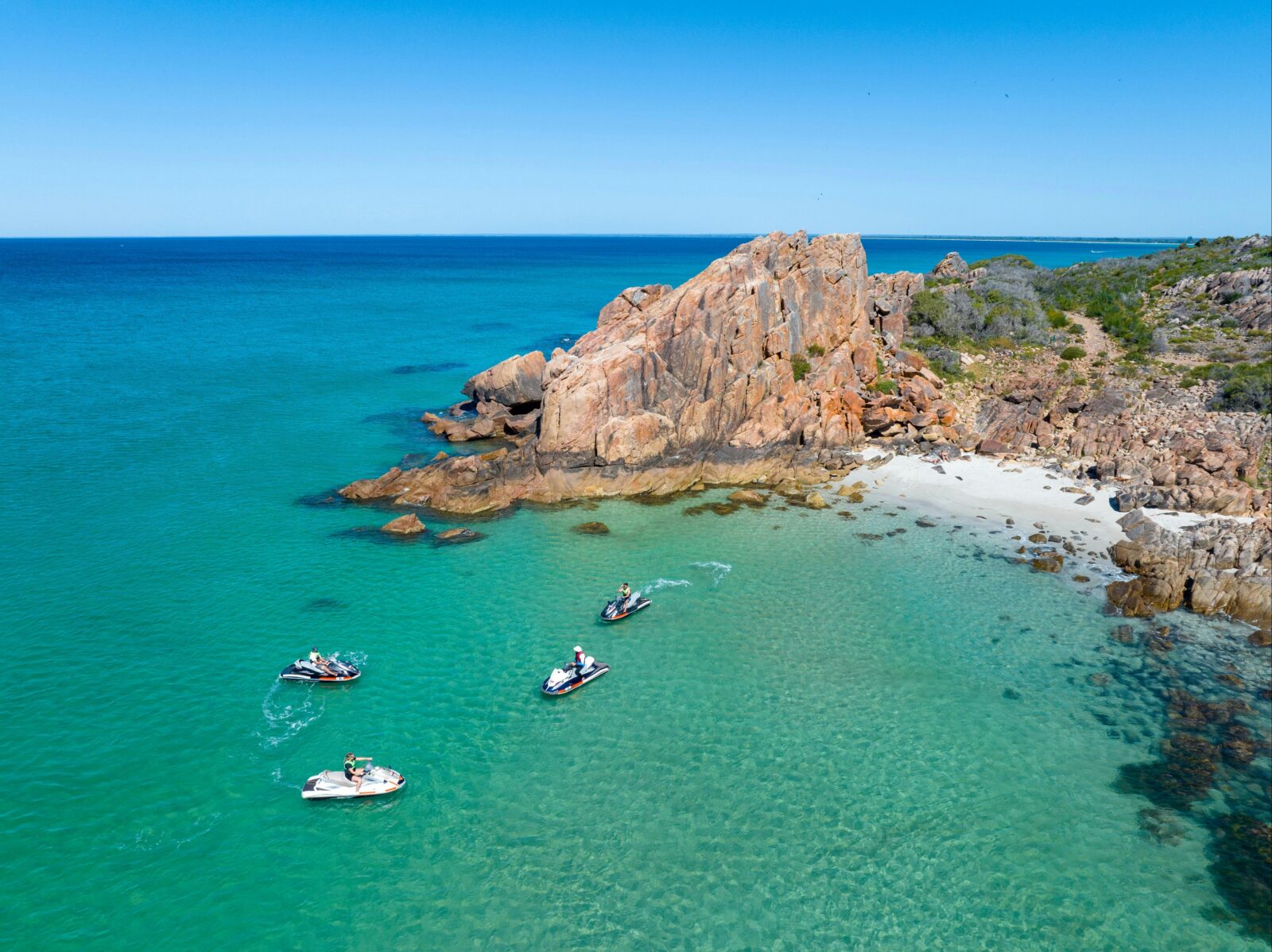 A group of four jet skis in the clear blue waters at Castle Rock